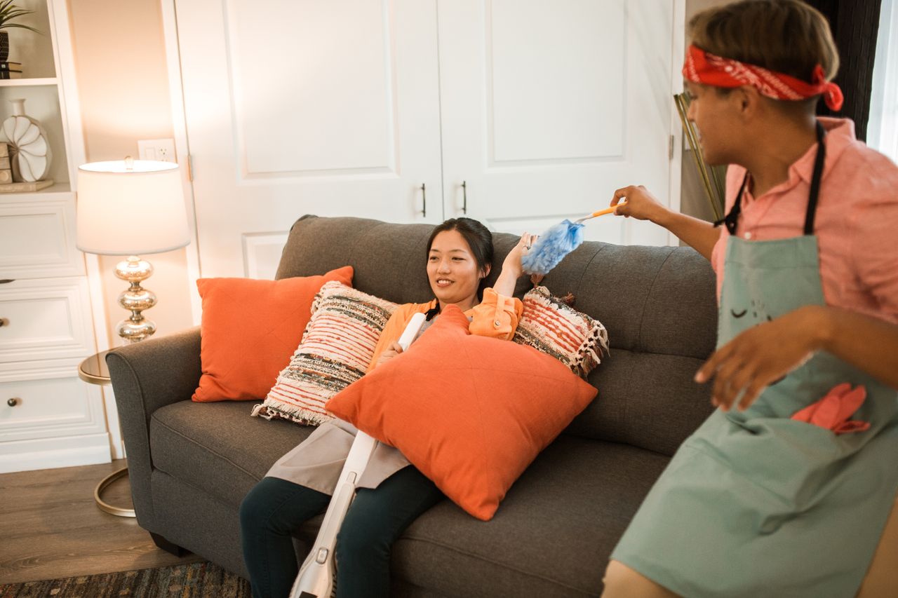 our-mission A cheerful couple having fun while playfully cleaning their living room together.